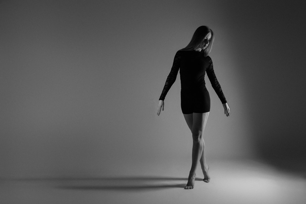 Dancer in standing position looking down toward left side black and white